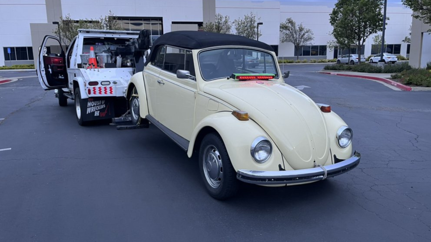 An old vw bug is parked in a parking lot