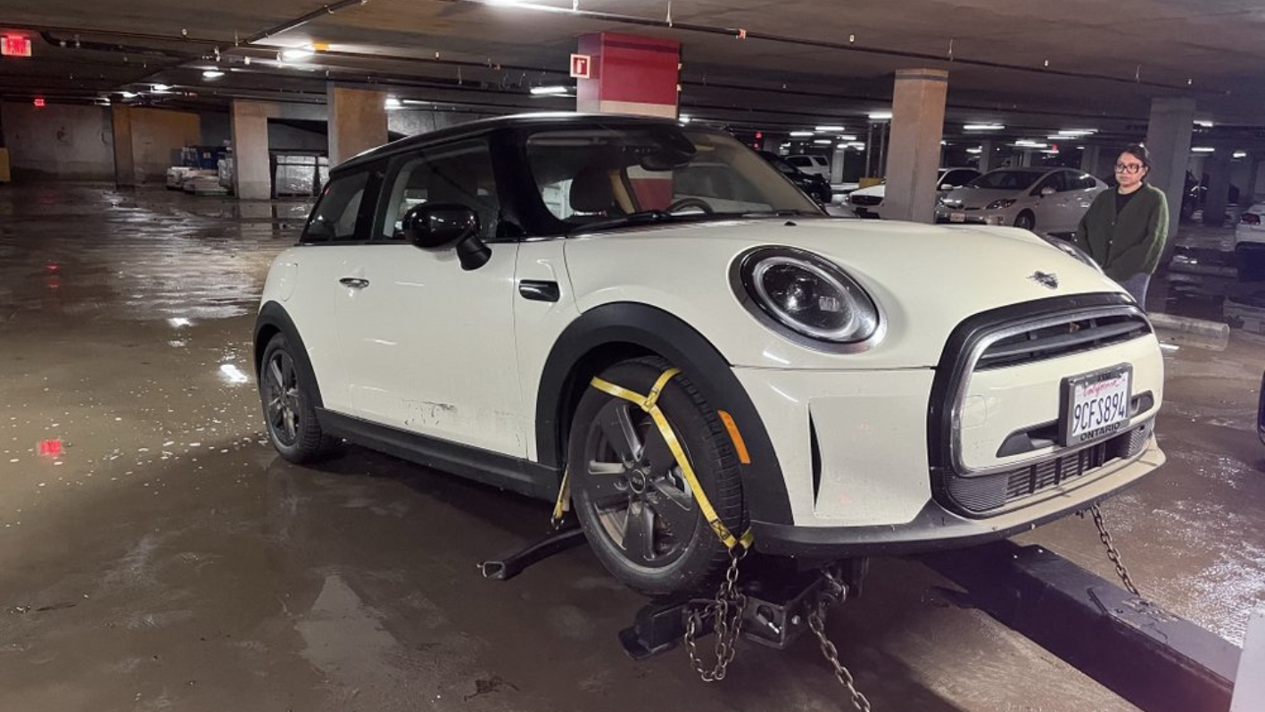 A man standing next to a white car in a parking garage